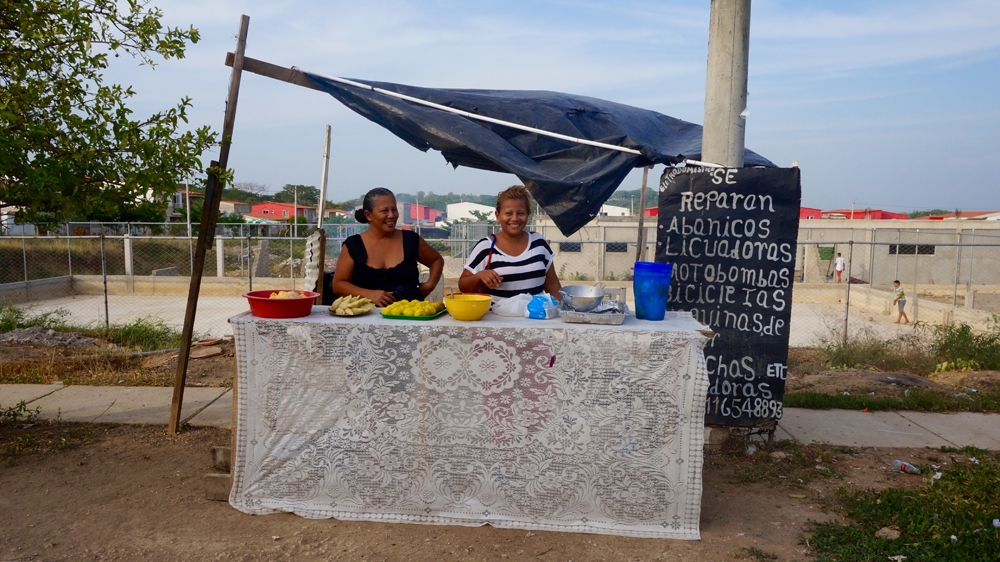 Dayanera and her daughter at the stand where they sell food to neighbours; opportunities to make money are limited, and often confined to the community itself. [Julia Zulver/Al Jazeera]