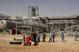 File photo of workers looking at journalists during a media tour of the Khurais oilfield