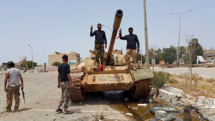 Members of the Libyan pro-government forces gesture as they stand on a tank in Benghazi
