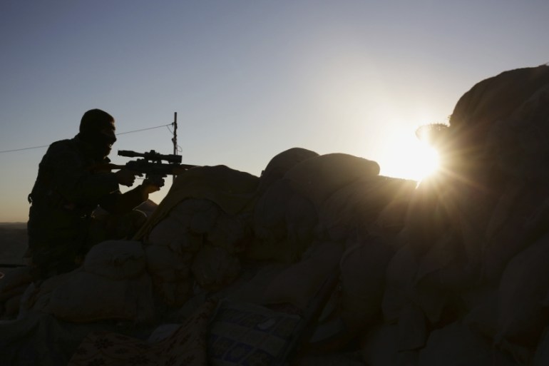 A Kurdish peshmerga fighter stands guard in fighting against ISIL as the sun rises in Sinjar, Iraq [AP]