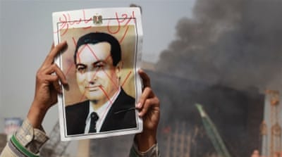 A protester in Tahrir Square holds a photo showing President Hosni Mubarak's face crossed out (2011) [Getty]