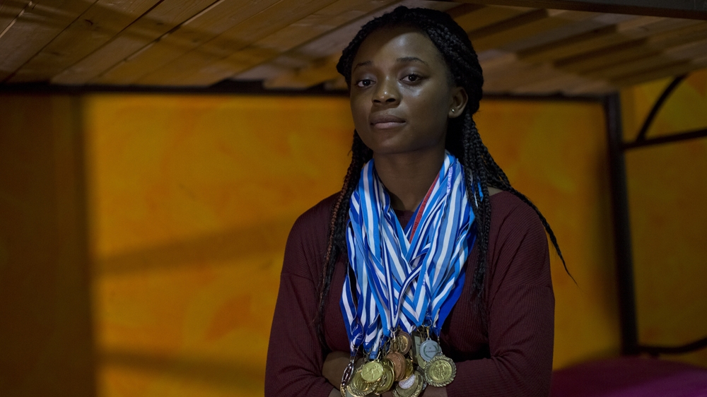 Jessica Ben Anosike, a second-generation migrant, wears a selection of her medals won in track and field events at her home in Athens [Anna Psaroudakis/Al Jazeera]