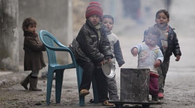 Children warm themselves around a fire during cold weather in Aleppo [Reuters]