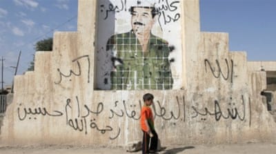 A boy walks past a picture of Iraq's former president Saddam Hussein on a street in Tikrit, Iraq [REUTERS]