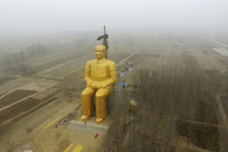 A crane is seen next to a giant statue of Chinese late chairman Mao Zedong under construction near crop fields in a village of Tongxu county, China