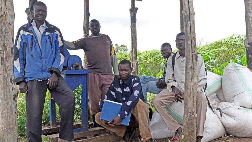 This cooperative, led by Simon Lomeriga (second left), struggles to grow enough food to meet local demand. Their food processor stands idle because of a lack of fuel. [Simona Foltyn/Al Jazeera] 