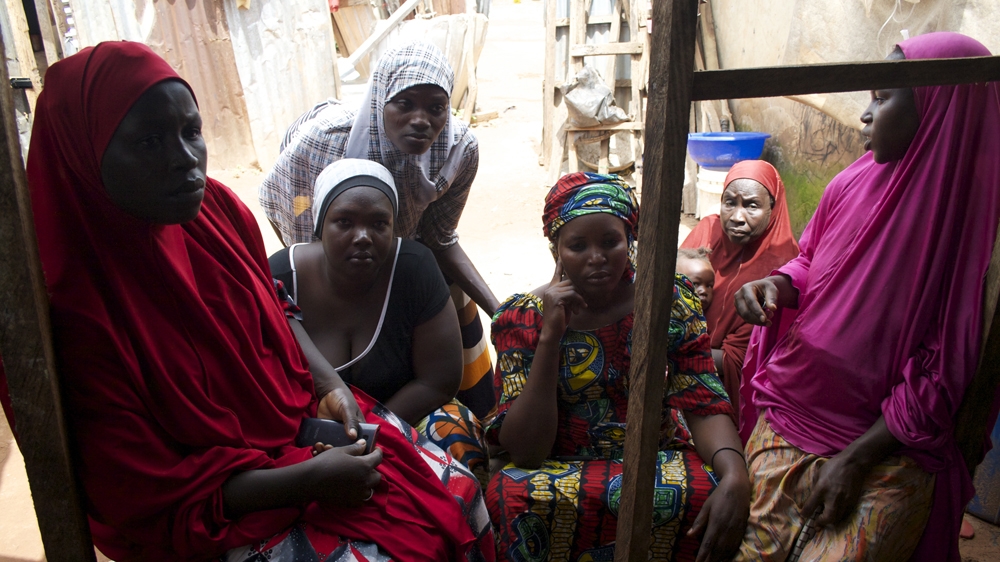 On the outskirts of Abuja, self-taught midwife Dada Nguru sits with women who fled with her from the town of Gwoza, in northeastern Nigeria [Caelainn Hogan/Al Jazeera]