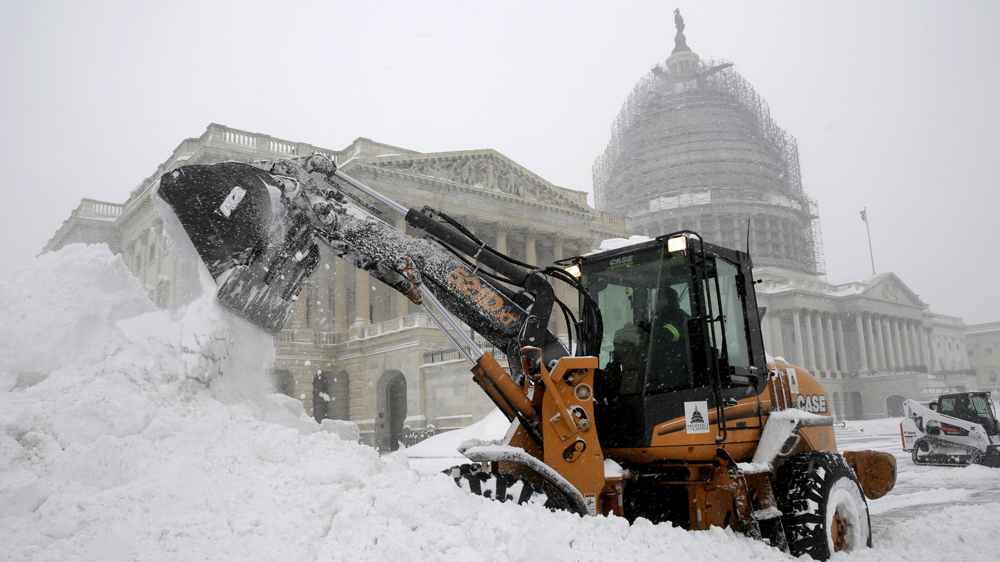 A Capitol Hill employee used a heavy earth-moving machine to clear snow during the winter storm in Washington [Reuters]