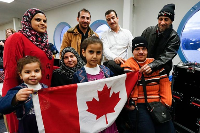 A Syrian refugee family, sponsored by a local group called Ripple Refugee Project, pose for photos in Toronto [Getty]