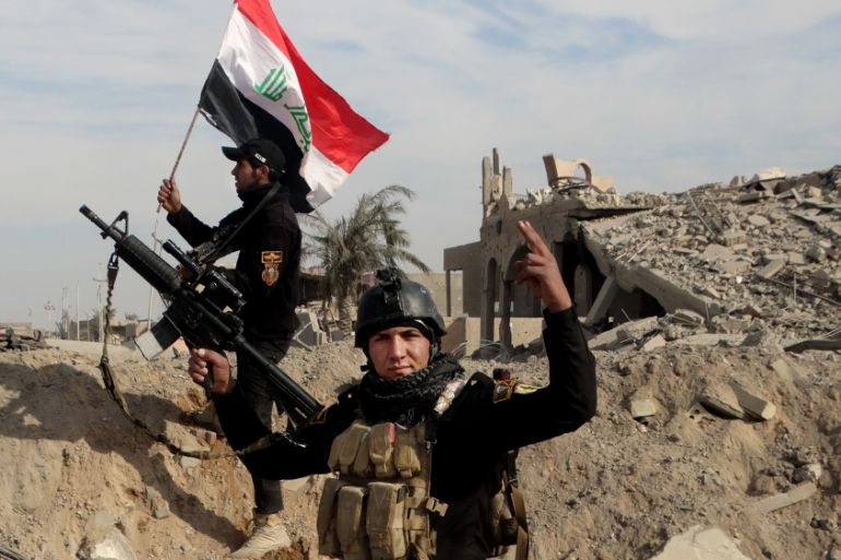 Iraqi security forces raise an Iraqi flag near the provincial council building in central Ramadi [AP]