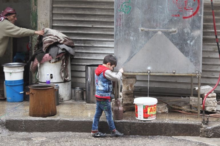 A boy fills containers with water from one of the reservoirs that were placed and supervised by the Syrian Arab Red Crescent and other humanitarian organisations in Aleppo