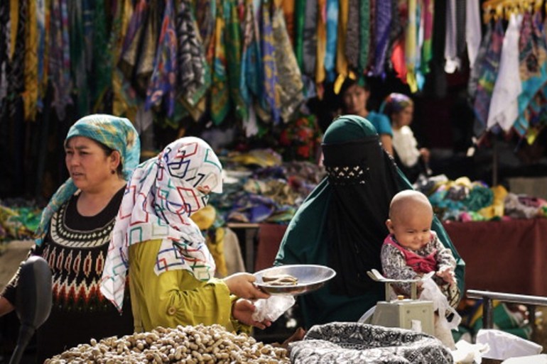 Uighur Muslim women trading food at the Turpan city market in Turpan, China [Getty]