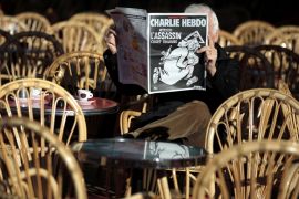 A man reads the latest edition of French weekly newspaper Charlie Hebdo with the title "One year on, The assassin still on the run" on a cafe terrasse in Nice