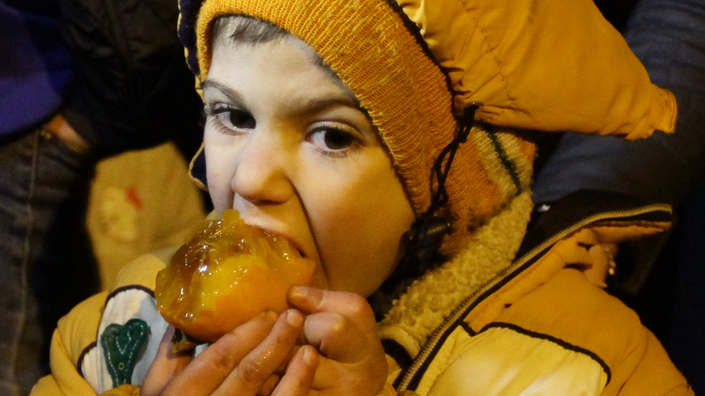 
A child eats a fruit on the outskirts of tMadaya after aid is delivered [Louai Beshara/AFP]
