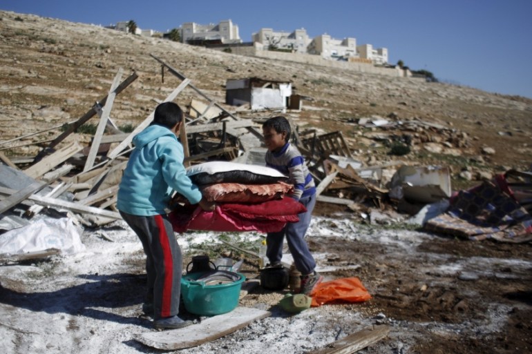 Palestinian boys carry their belongings after the Israeli army demolished their shanty, that their family lives in, near the Israeli West Bank settlement of Maale Adumim, near Jerusalem