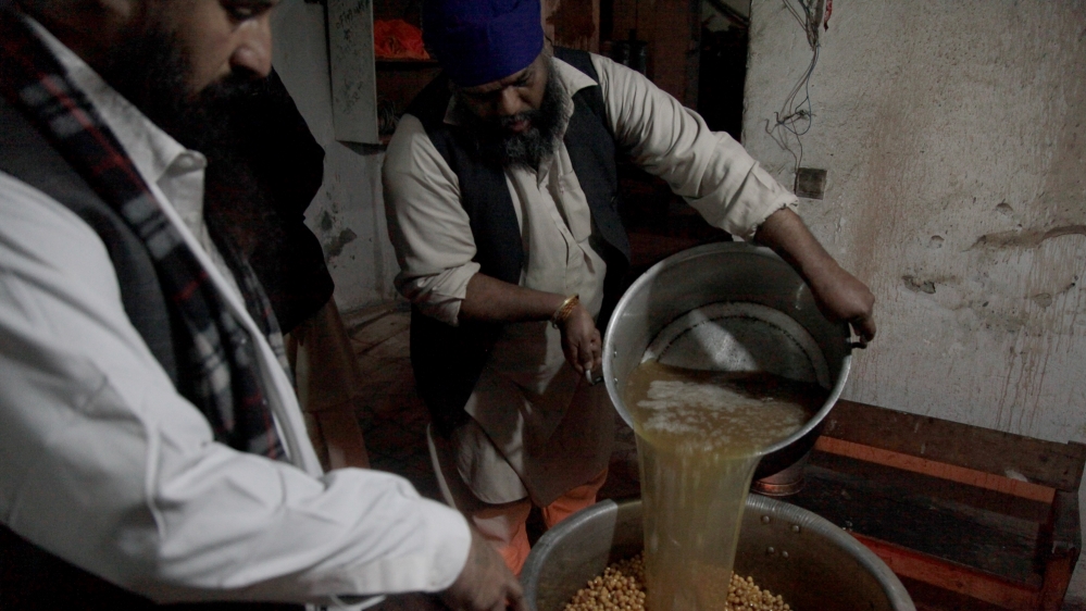 Mukesh and Sivender Singh, another resident of Kabul's Karte Parwan Gurdwara, prepare chole, a chickpea curry, for the morning langar [Sune Engel Rasmussen/Al Jazeera]