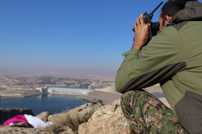 A fighter from the Democratic Forces of Syria takes an overwatch position at the top of Mount Annan overlooking the Tishrin dam, after they captured it on Saturday