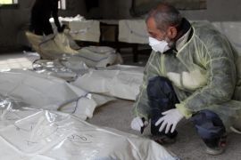 A coroner writes on a body bag at a morgue in Aleppo