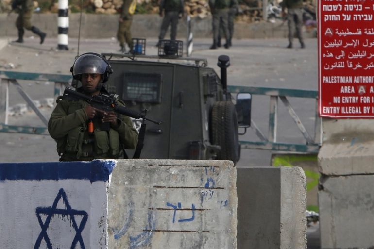 Israeli soldier stands guard near the scene where a Palestinian, who the Israeli military said tried to stab an Israeli soldier, was killed by Israeli troops, near Hebron