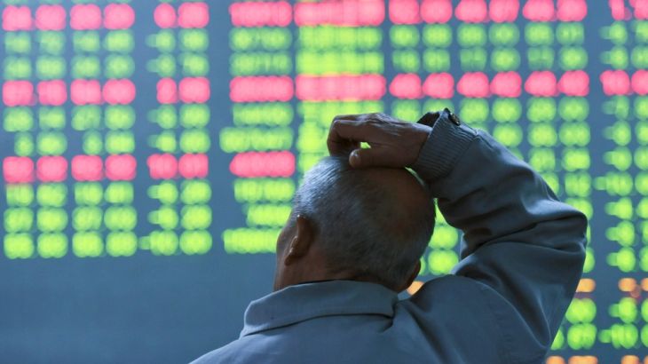 An investor looks at an electronic screen showing stock information at brokerage house in Hangzhou