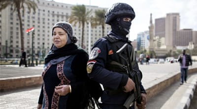 A woman walks past an Egyptian policeman, on the eve of the fifth anniversary of the January 25, 2011 uprising in Tahrir Square, Cairo, Egypt. [AP]