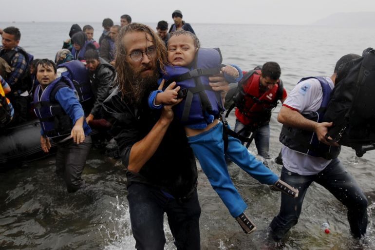 File photograph shows a volunteer carrying a Syrian refugee child off an overcrowded dinghy at a beach after the migrants crossed part of the Aegean Sea from Turkey to the Greek island of Lesbos