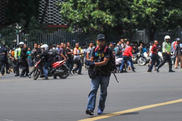 A man is seen holding a gun as people run away in central Jakarta, Indonesia [Reuters]