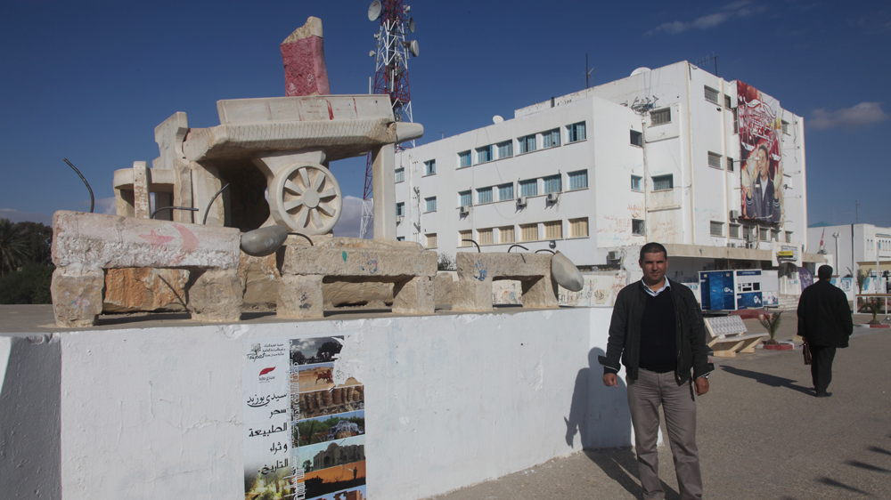 Ali Bouazizi stands beside a stone monument to his cousin, Mohamed Bouazizi, in Sidi Bouzid [Thessa Lageman/Al Jazeera]