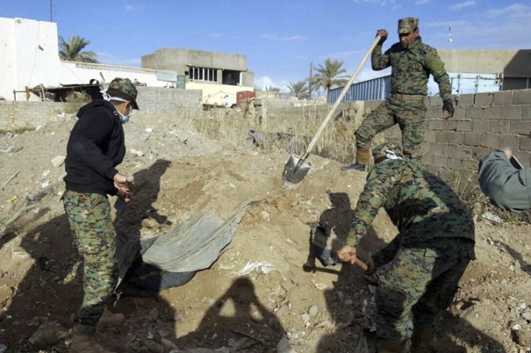 Iraqi security forces members work at the site of a mass grave grave believed to contain the bodies of Iraqi civilians killed by Islamic State group militants in Ramadi