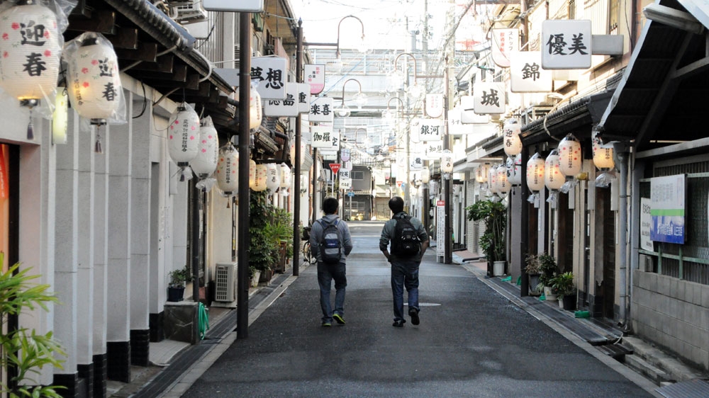A yakuza-run red-light district in Osaka that straddles Kamagasakidoya-gai. The signs amid lanterns on either side of the street advertise prostitution [Joe Jackson/Al Jazeera]