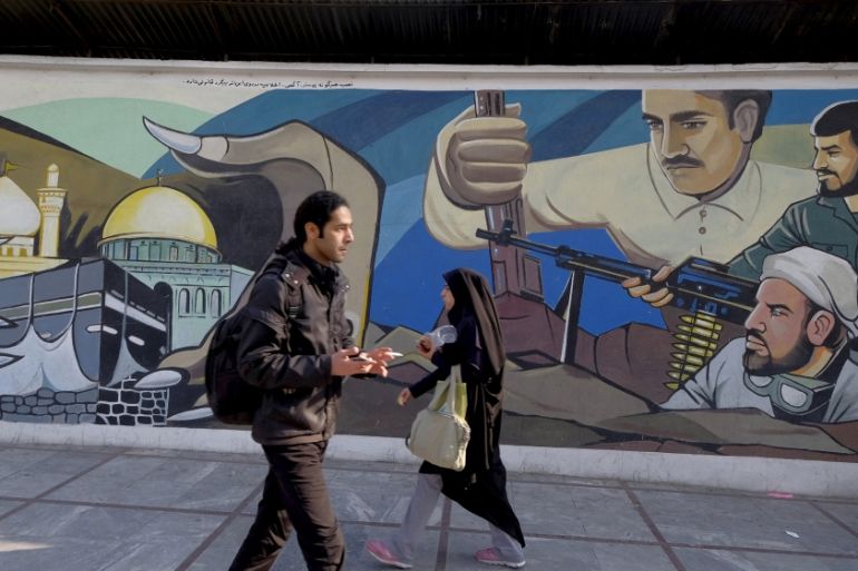 Iranians walk past a revolutionary mural in Tehran, Iran [REUTERS]