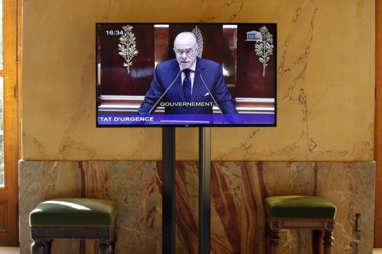 French Interior Minister Bernard Cazeneuve is seen on a screen as he speaks during a debate to extend a state of emergency in France at the National Assembly in Paris