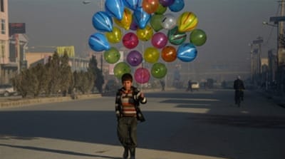 Afghan boy walks as he looks for customers to buy his balloons on the streets of Mazar-i-Sharif [Getty]