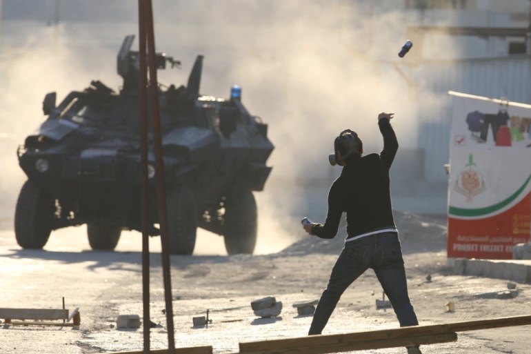 A protester throws a glass bottle containing paint at a riot police APC during anti-government clashes in Sitra