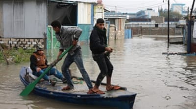 Palestinians paddle a boat in flood waters as they make their way to their flooded chicken farm during a winter storm in Rafah in the southern Gaza Strip [REUTERS]