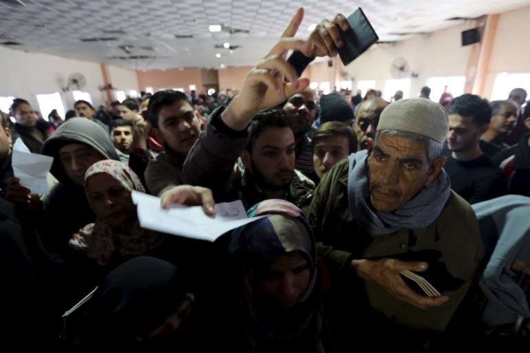 Palestinians present their documents as they wait for travel permits to cross into Egypt at the Rafah border crossing between Egypt and the southern Gaza Strip [REUTERS]