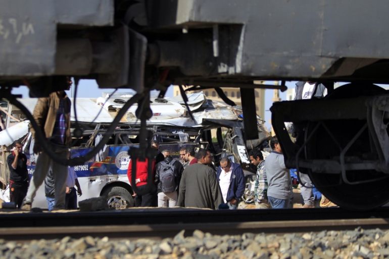 People look at the wreckage of a school bus which crashed with a train northeast of Cairo