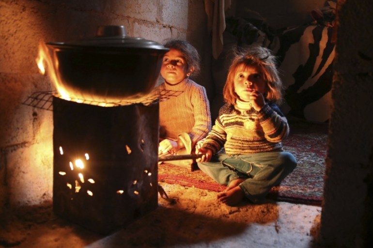 Children warm themselves around a fire in eastern Ghouta near Damascus
