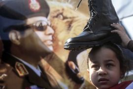 A supporter of Egypt''s President Abdel Fattah al-Sisi in the upcoming elections, holds a military boot on her head in a sign of support for military rule in 2014 [AFP]