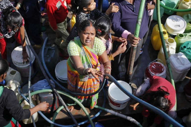 Residents fill their empty containers with water from a municipal tanker in New Delhi