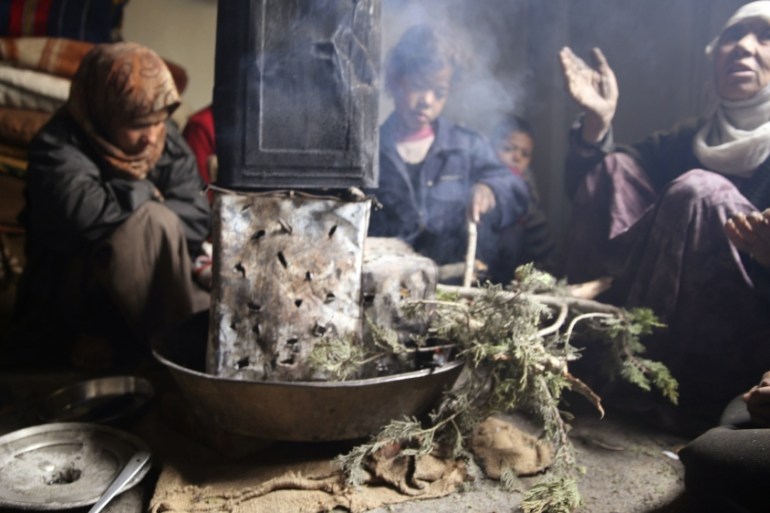 Family warms themselves around a fire in eastern Ghouta near Damascus