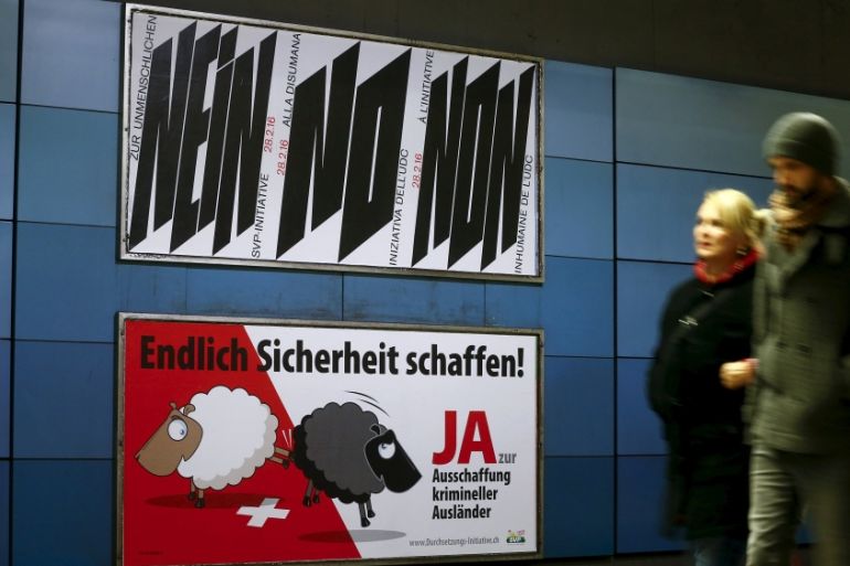 A poster of Swiss SVP, demanding to vote for an initiative to deport criminal foreigners, is placed underneath another one against it in Zurich