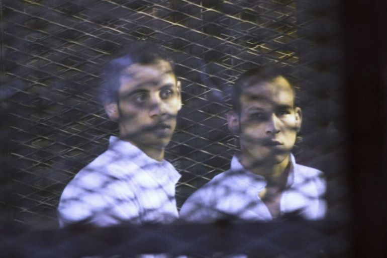 Defendants react as they are seen behind bars during their hearing at a court in Cairo