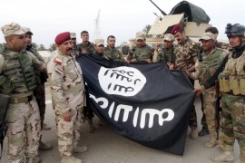 Iraqi security forces stand with an Islamic State flag in Ramadi