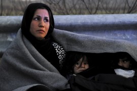 An Afghan mother covers herself and her children with a blanket while trying to reach the Greek-Macedonian border, following reports that Macedonia has closed its borders with Greece to Afghan migran