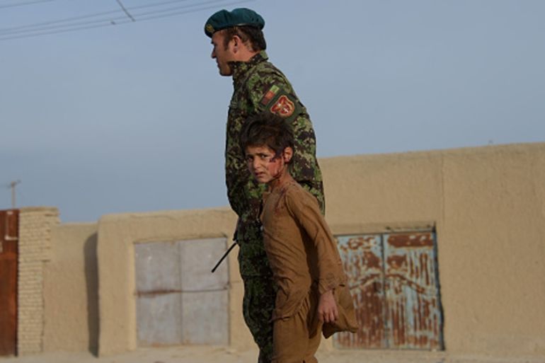 A wounded Afghan boy walks with an Afghan National Army (ANA) soldier at the site of a suicide attack in Dehdadi, a district close to the provincial capital Mazar-i-Sharif [Getty]