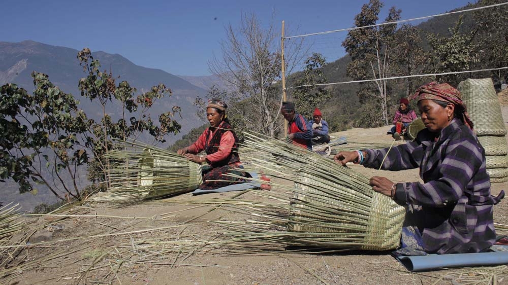 Separated from their agrarian routine, Tiru villagers living at the Kalikasthan IDP camp keep themselves occupied. Bamboo is among the few resources the local community allows Tiru villagers to use [Niranjan Shrestha/Al Jazeera]
