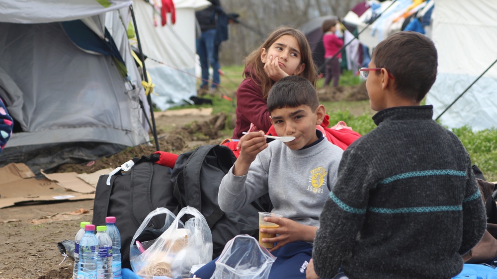 Children eat soup at a petrol station 20km from the Greek border with former Yugoslav Macedonia [John Psaropoulos/Al Jazeera]