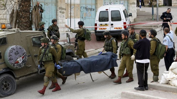 Israeli soldiers carry the dead body of one of two Palestinians, whom the Israeli military said were shot dead by Israeli troops after they attacked an Israeli soldier, in Tal Rumaida in Hebron
