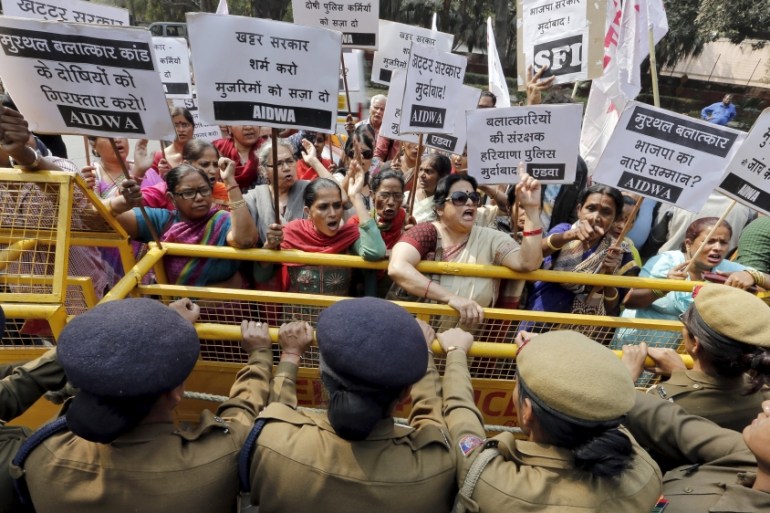 Activists from AIDWA shout slogans behind a police barricade outside the Haryana Bhawan during a protest in New Delhi